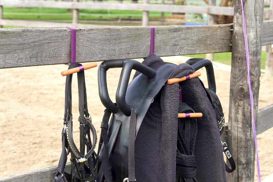 HIT Saddle Hang holding a saddle, bridle and helmet on a fence rail